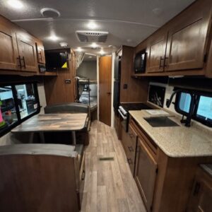 Interior view of a modern RV with kitchen and dining areas.