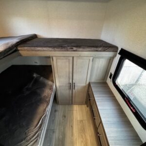 Compact camper van interior with beds, storage, and window seating.