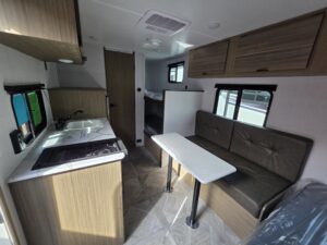 Compact RV interior with kitchenette and seating.
