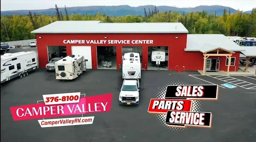 A red service center with RVs parked outside, advertising sales, parts, and service.
